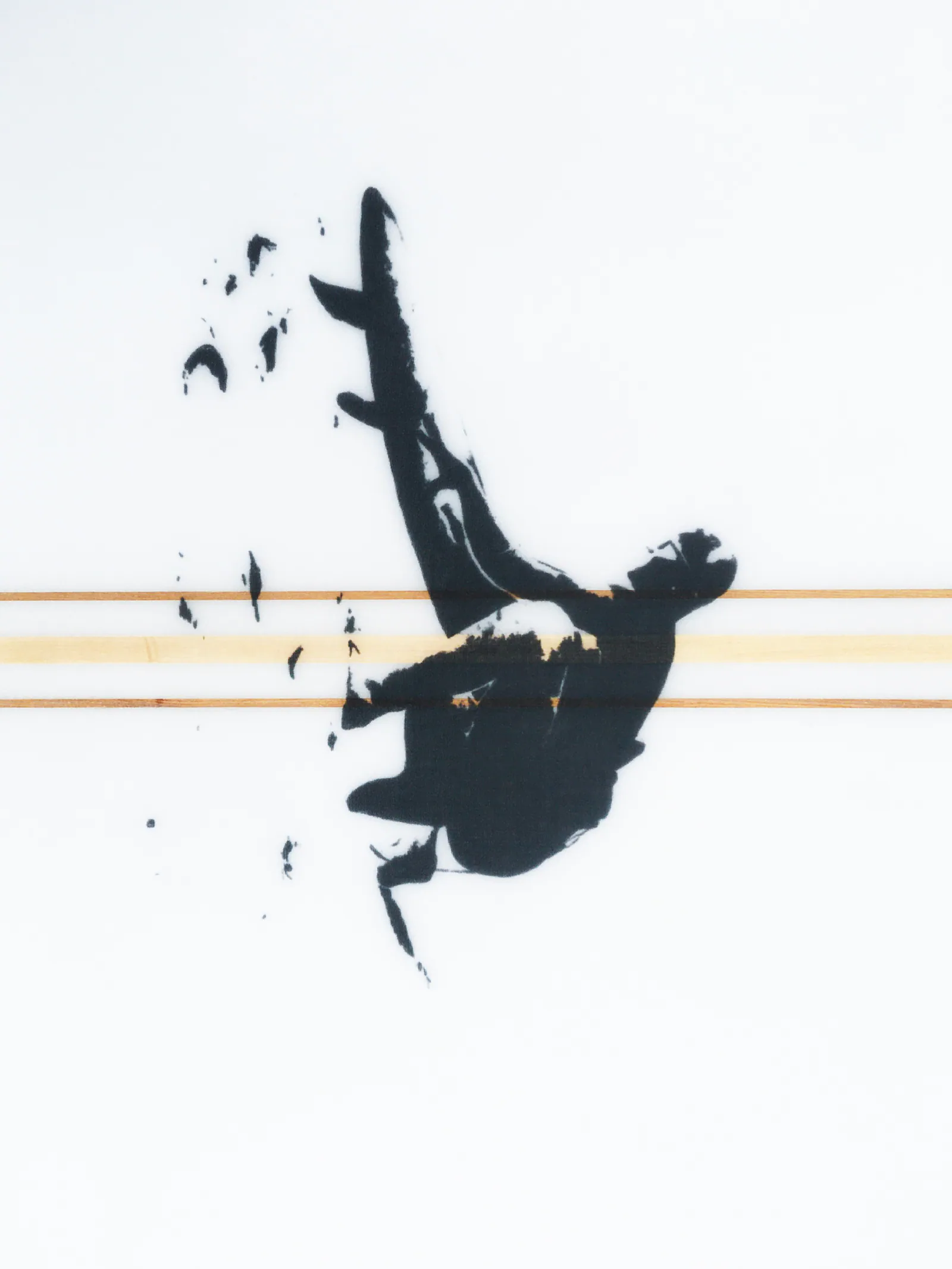 Gros plan, planche vue en travers : silhouette noire d’un surfeur accroupi qui tient sa planche, entourée de petites éclaboussures