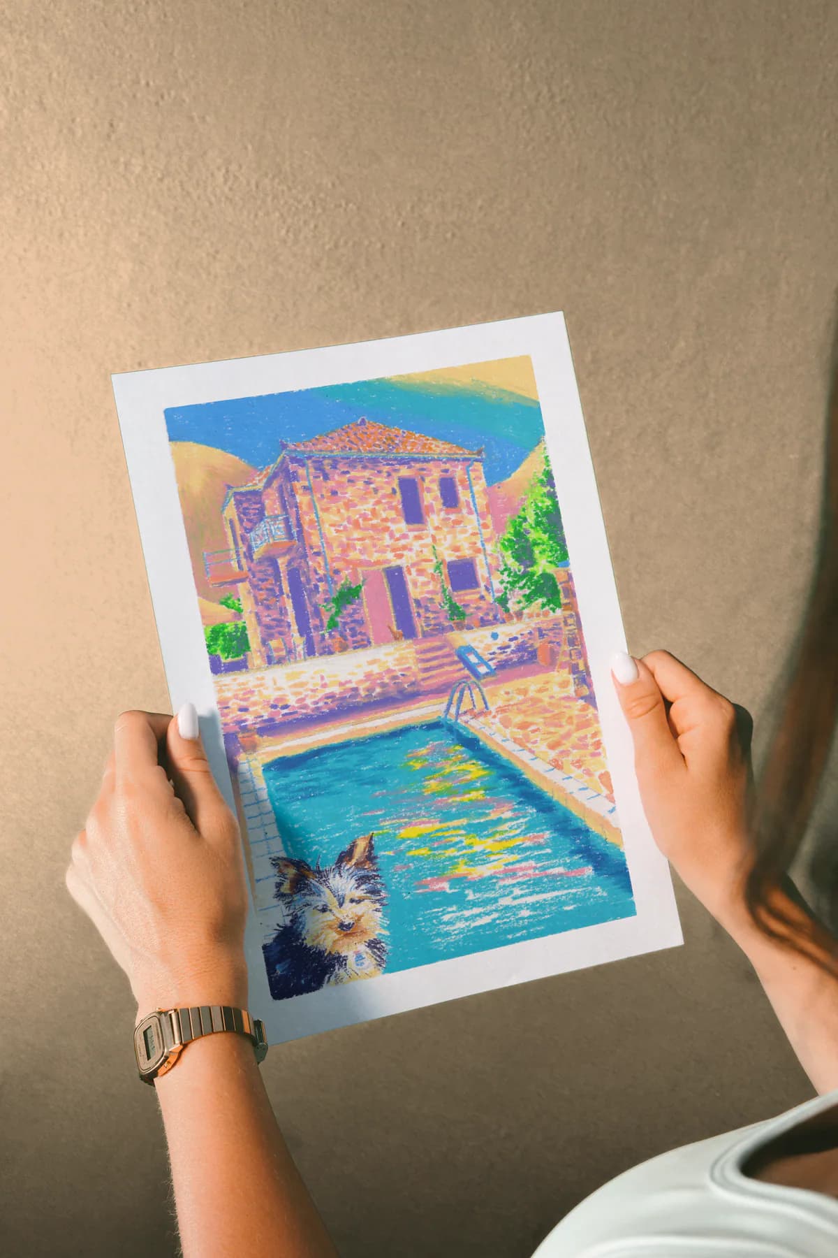 Le print Chien maison tenu à deux mains devant un mur beige.